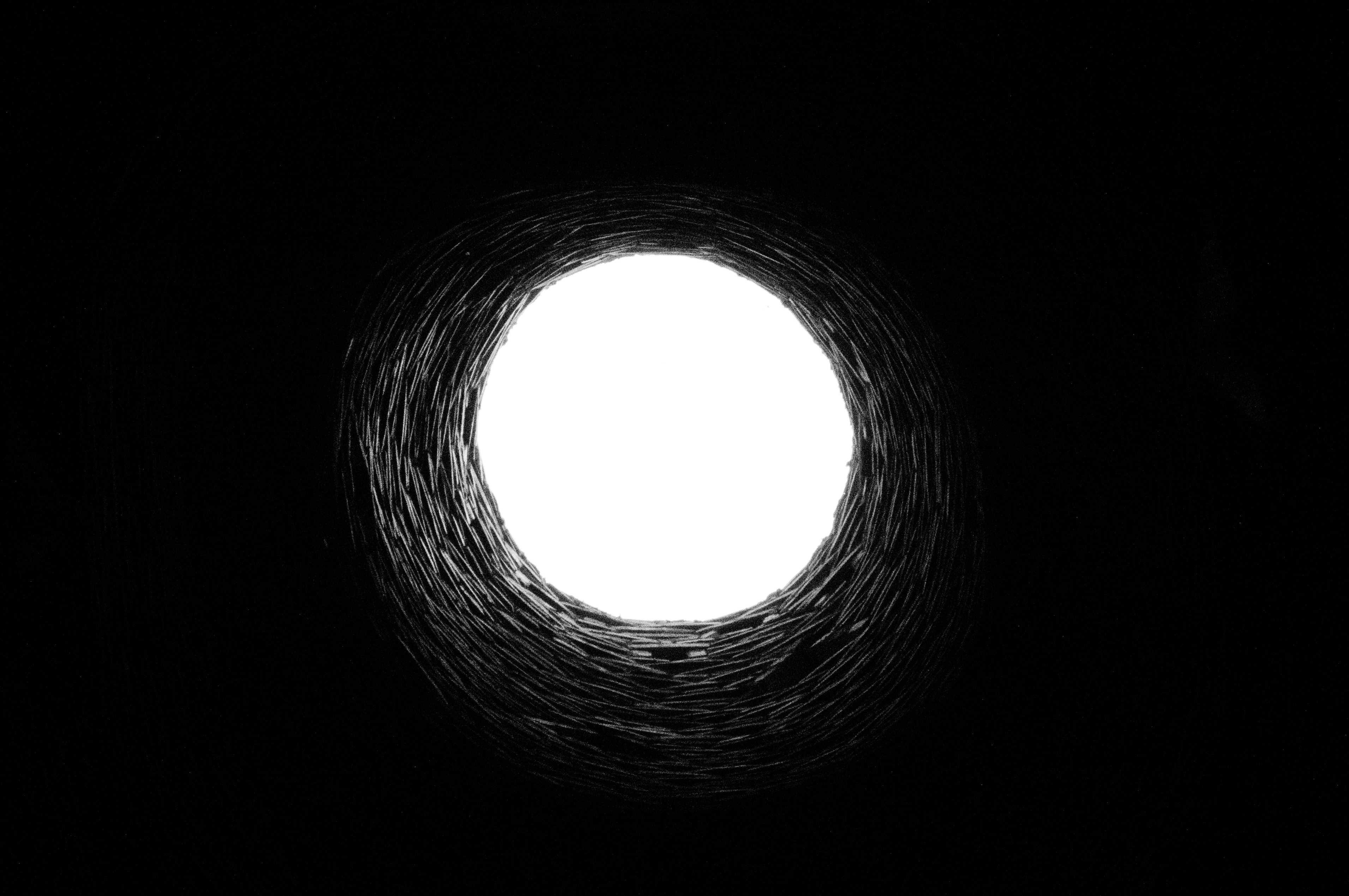 The view from within a deep dark hole, entirely black with a big white circle in the middle